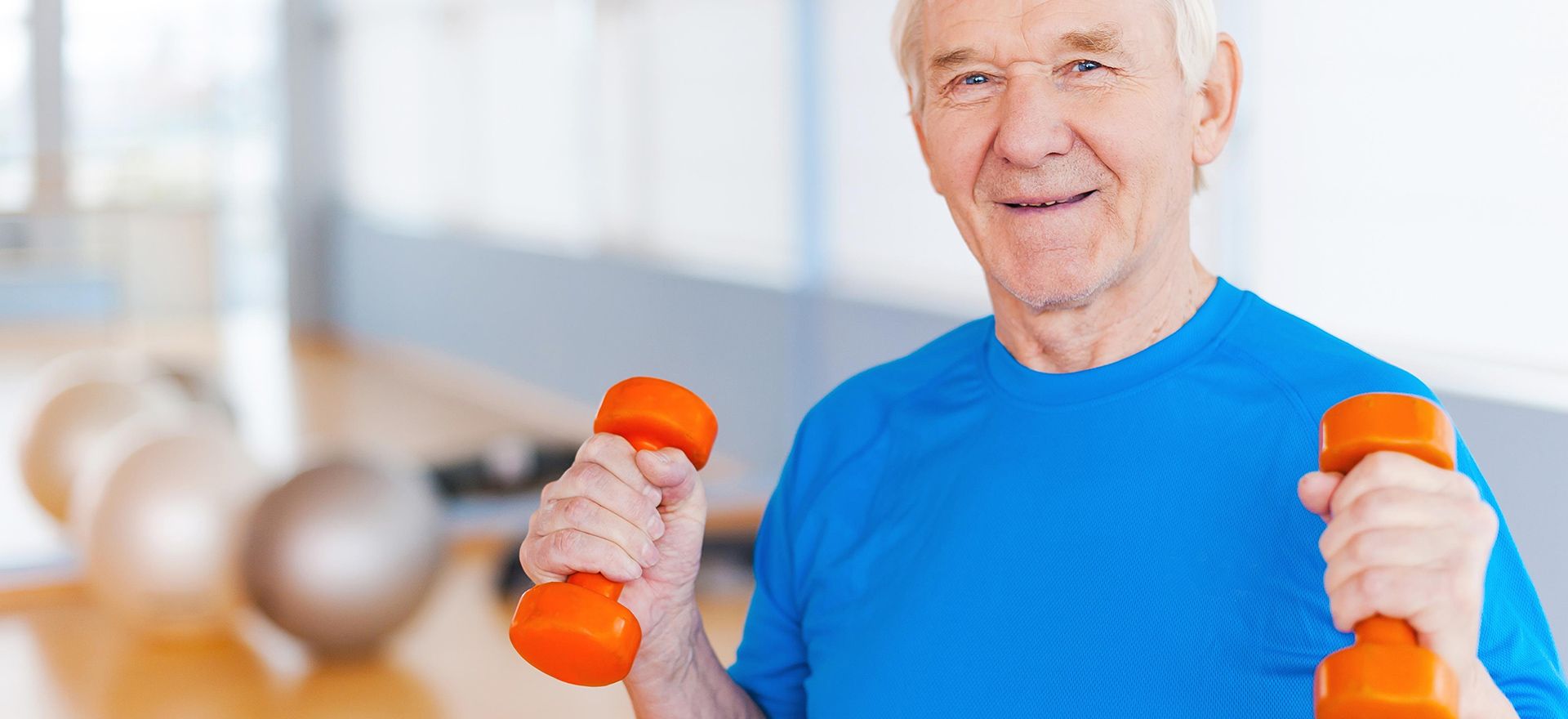 Happy senior man exercising with dumbbells